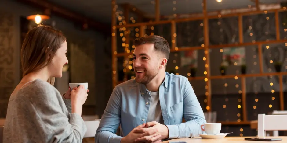 Ein Paar sitzt in einem Café und lächelt sich bei einem Date an.