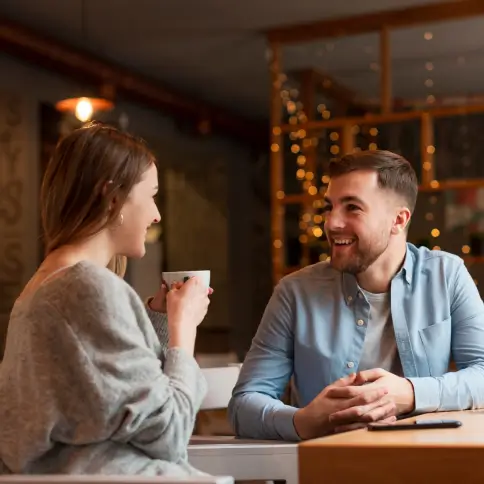 Ein Paar sitzt in einem Café und lächelt sich bei einem Date an.