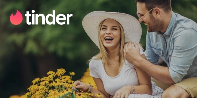 Das Tinder-Logo über einem Paar, das zusammen lacht