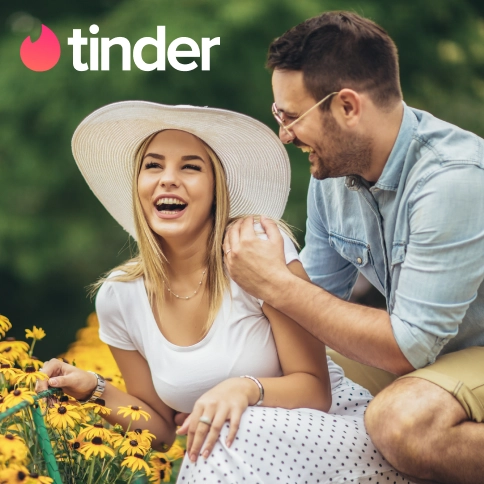 Das Tinder-Logo über einem Paar, das zusammen lacht